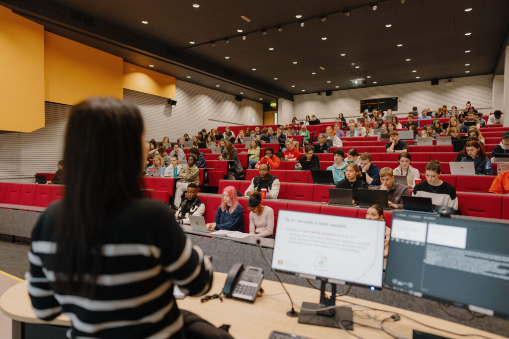 Lecturer giving lecture in lecture theatre full of students